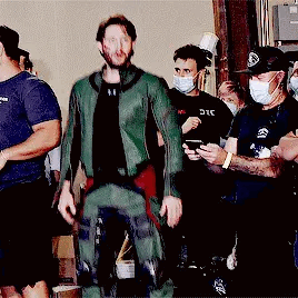 Man in Green Suit Standing Before Masked Group