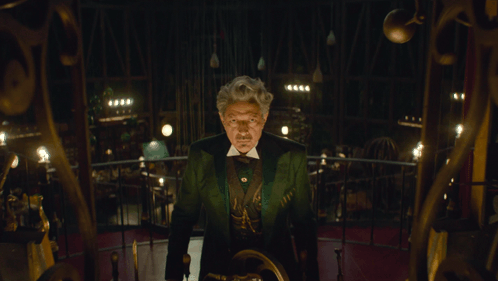 Man in Green Suit Staring in Dark Room