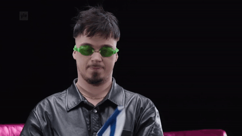 Man in Green Sunglasses Holding Small Flag