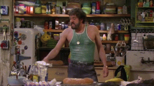 Man In Green Tank Top In Messy Kitchen GIF