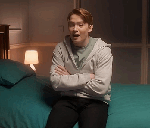 Man in Grey Hoodie Arms Crossed on Bed
