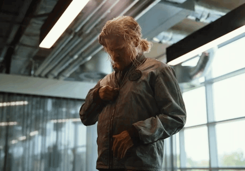 Man in Grey Jacket Standing in Front of Glass Wall
