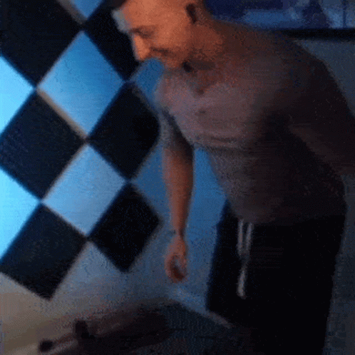 Man in Grey Shirt in Front of Checkered Wall