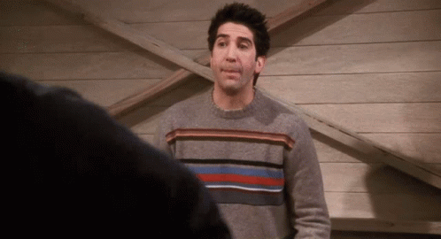 Man in Grey Striped Sweater in Front of Wooden Wall