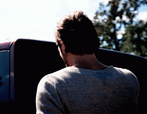 Man In Grey Sweater In Front Of Black Vehicle GIF