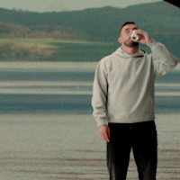 Man in Grey Sweatshirt Drinking from Can