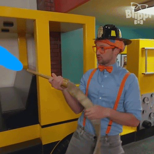 Man In Hard Hat And Suspenders Holding Stick In Front Of Blippi Building GIF
