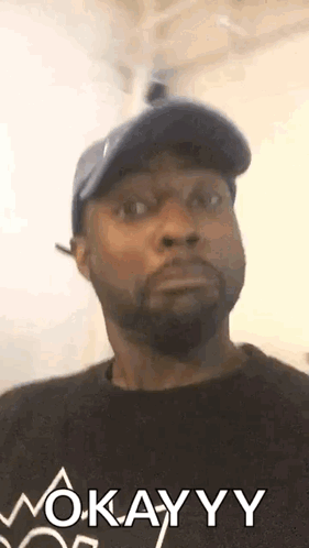 Man in Hat and Black Shirt Saying Okay