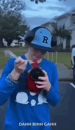 Man in Hat and Headphones Drinking With Spoon in Mouth