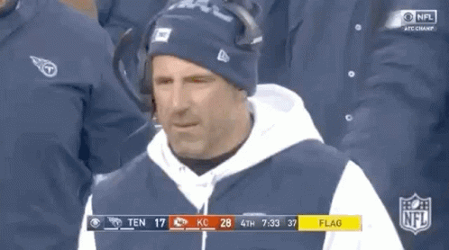 Man in Hat and Hoodie in Front of NFL Scoreboard