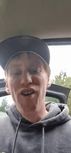 Man In Hat And Hoodie Making Funny Face In Car GIF