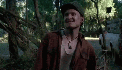 Man In Hat And Necklace Smiling In Woods GIF