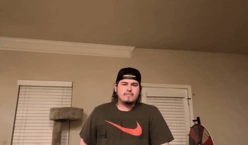 Man in Hat and Nike Shirt Near Cat Tree