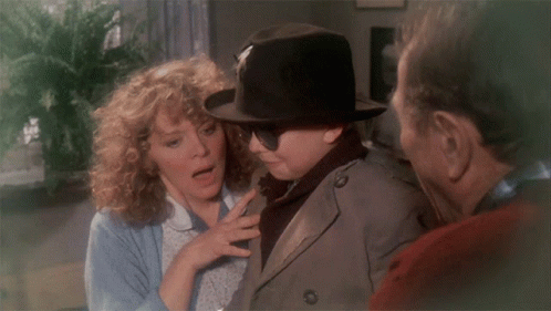 Man in Hat and Sunglasses Talks to Woman and Trench Coat Man