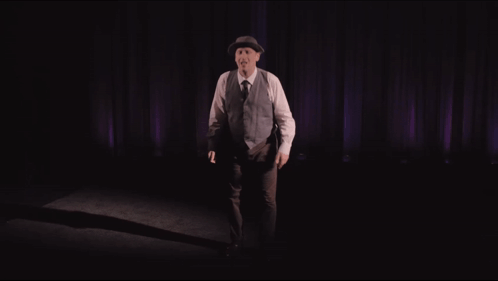 Man in Hat and Vest Purple Curtain Alone