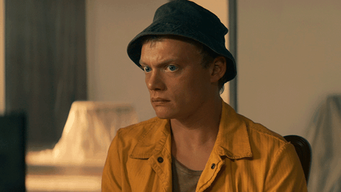 Man in Hat and Yellow Jacket Sitting in Chair