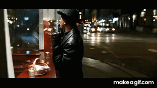Man in Hat Looking Out Window at City Night