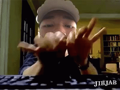 Man in Hat Making Peace Sign at Keyboard