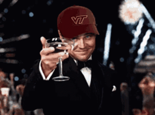 Man in Hat Saying VT Holding Wine Glass