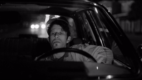 Man in Hat Sitting in Car at Night