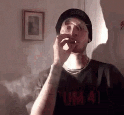 Man in Hat Smoking Cigarette in Living Room