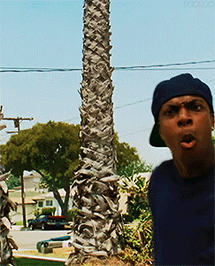 Man In Hat Standing By Palm Tree In Residential Area GIF