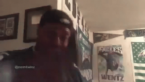 Man in Hat Standing in Front of Poster Wall