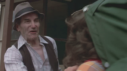 Man in Hat Talking to Man Outside House