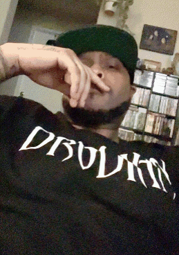Man in Hat Wearing Dbolmn Shirt Smoking Cigarette