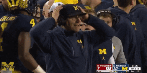 Man in Hat With Letter M Watching Football Game