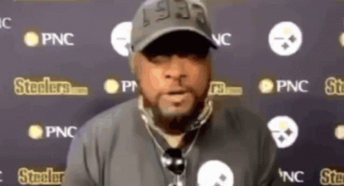 Man in Hat With Microphone in Front of Steelers Logos
