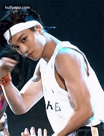 Man in Headband and Tank Top Flexing on Stage