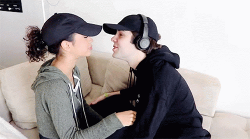 Man in Headphones and Baseball Cap Kissing Woman on Cheek