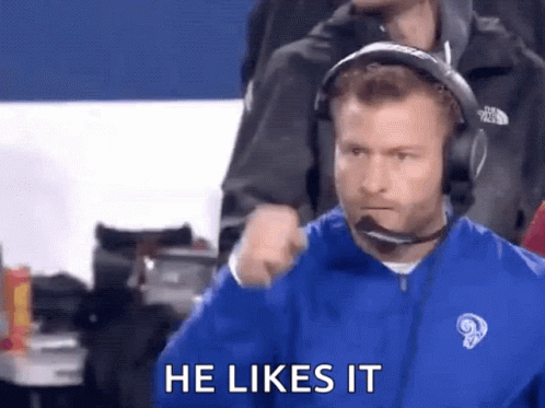 Man in Headphones and Blue Jacket Says He Likes It During Football Game