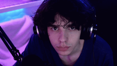 Man in Headphones and Blue Shirt Pointing at Camera