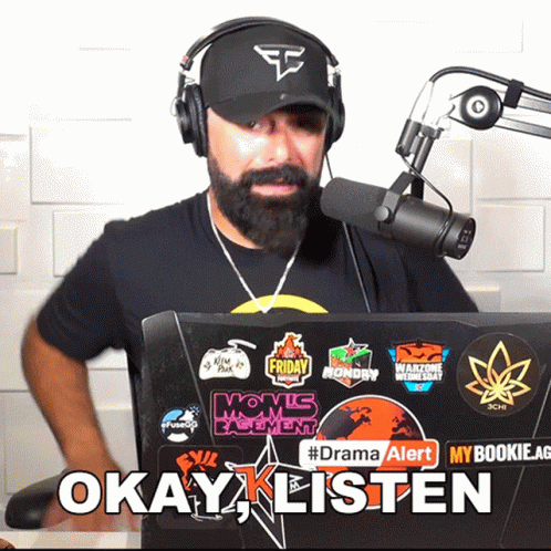 Man in Headphones and Hat in Front of Laptop Says Okay Listen