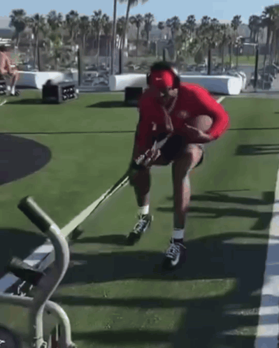 Man in Headphones and Red Nike Hat Holding Hockey Stick