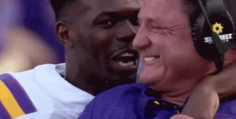 Man in Headphones Hugging Football Player in Purple and Yellow Jersey