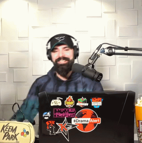 Man in Headphones in Front of Microphone and Laptop Says Drama Alert