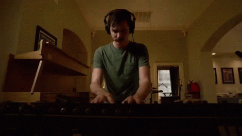 Man In Headphones Playing Keyboard In Living Room GIF