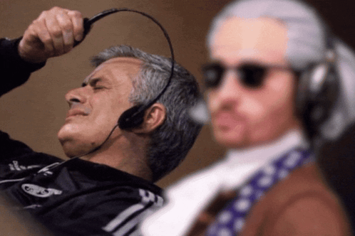 Man in Headset Looks at Man in Wig