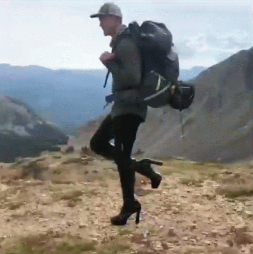 Man In High Heels And Backpack On Hill GIF