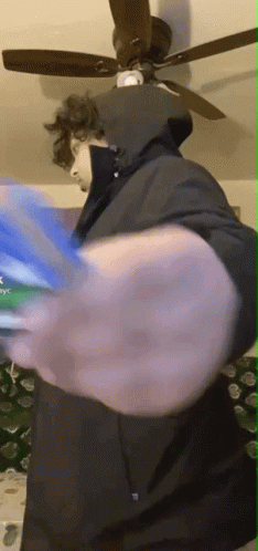 Man in Hooded Jacket Playing Video Game With Ceiling Fan