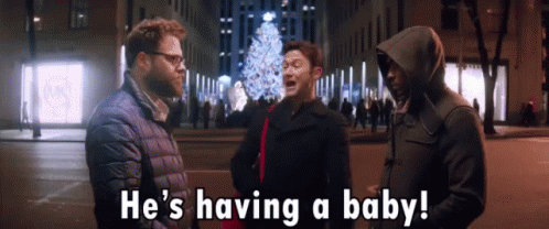 Man in Hooded Jacket Says Having a Baby in Front of Christmas Tree