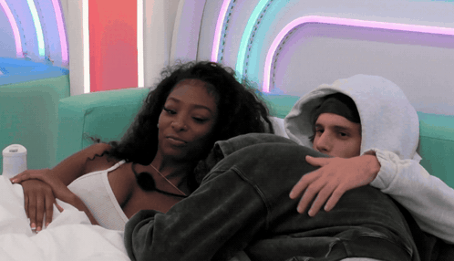 Man in Hoodie and Woman Laying on Couch