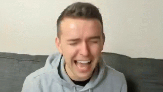 Man in Hoodie Laughing on Couch