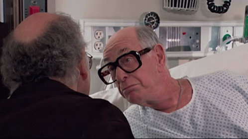 Man in Hospital Gown Looking at Man with Glasses