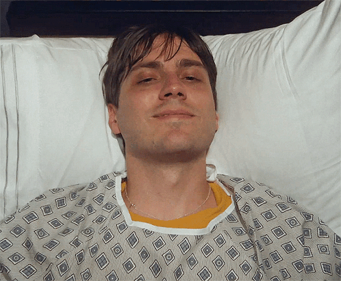 Man in Hospital Gown Smiling in Bed