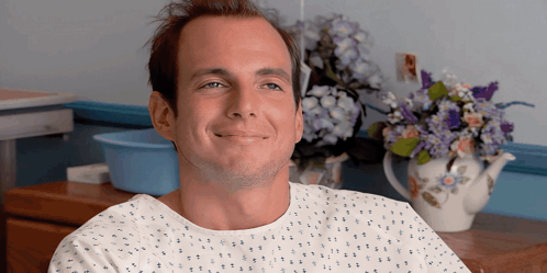 Man in Hospital Gown Smiling With Flowers