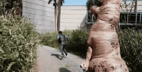 Man In Inflatable T-Rex Costume Running GIF